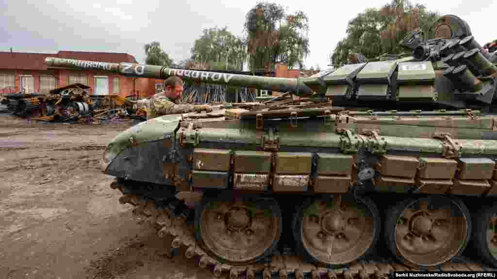 Тут же поруч українські військові лагодять трофейний російський танк 