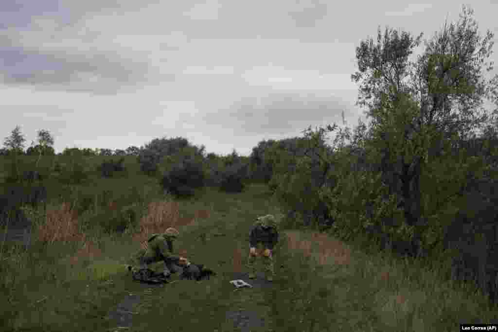 Українські військові оглядають тіло одного з українських військовослужбовців, очевидно, убитого кілька днів тому у відвойованому районі  