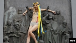 Активістка Femen Анна Алляйн вилізла на пам’ятник Київському князеві Володимиру із написом на грудях «Путін вбиває». Київ, 27 липня 2017 року