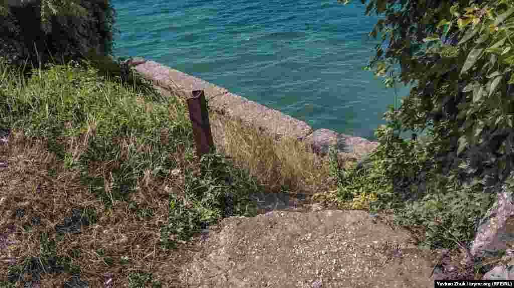 Піщаний пляж розташований поруч із російською військовою частиною. Спуститися на нього можна тільки дома необладнаними кам'янистими стежками, де з грунту стирчать шматки металевої арматури