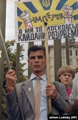 Чоловік тримає транспарант і прапор США в очікуванні на проїзд кортежу американського президента Джорджа Буша, який прибув із візитом до України. Київ, серпень 1991 року