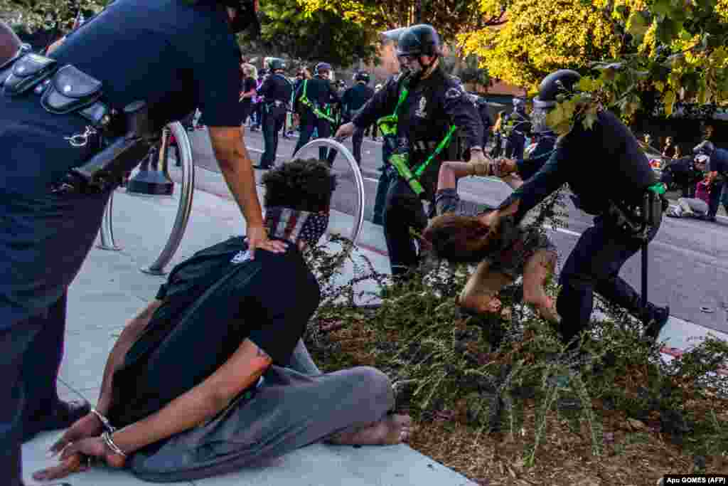 У центрі Лос-Анджелеса, штат Каліфорнія, поліцейські затримують чоловіка, особу якого не встановлено (ліворуч) та Лоріс Терчеро під час акцій пам'яті Джорджа Флойда (який загинув під час затримання поліцейськими), Бреони Тейлор (у березні жінка загинула, після того, як поліцейські увірвались до її будинку з вимогою видати підозрюваного, який вже був під вартою) та на знак солідарності з протестами у Портленді