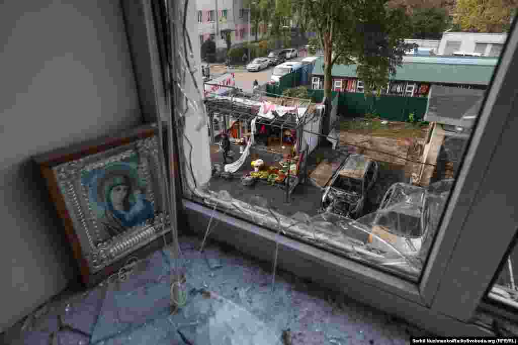 На фото – вигляд з вікна, яке розбилося внаслідок влучання уламків дрона і травмувало чоловіка. Також з вікна видно й інші наслідки обстрілу Києва – згорілі автівки та пошкоджені торгівельні приміщення у Солом'янському районі столиці