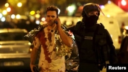 Эпизод террористического нападения в Париже: полицейский сопровождает пострадавшего