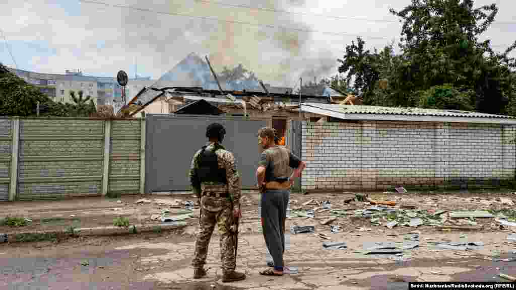 Поліцейський розмовляє з місцевим жителем біля його будинку, який був знищений артобстрілом з боку російської армії