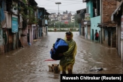 Мужчина с сумкой в руках пробирается по затопленной улице в Катманду, Непал, 4 октября 2025 года