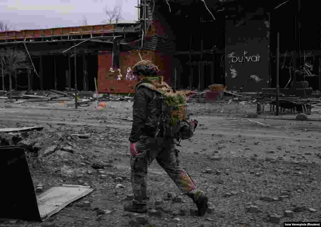 Український військовий на одній із вулиць Покровська. Позаду – зруйнована внаслідок обстрілу будівля.  