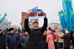 Учасник мітингу з плакатом біля монумента Незалежності в Алмати. 16 грудня 2019 року