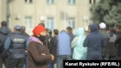 Женщина идет мимо участников протестов, начавшихся в Кыргызстане после парламентских выборов. Бишкек, 10 октября 2020 года.