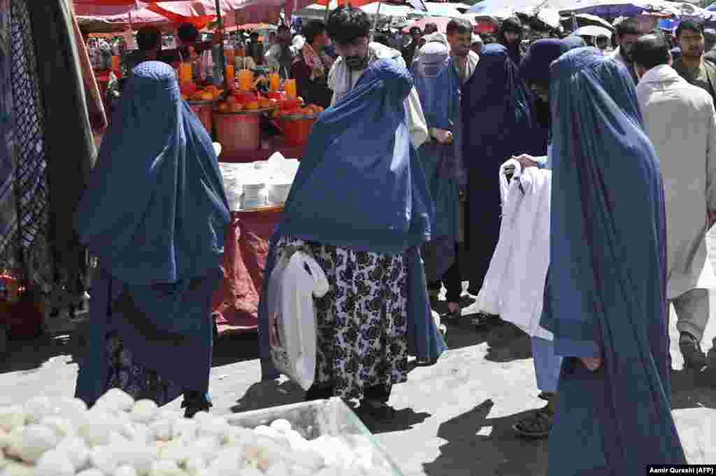 Burqa-clad women shop at a market in Kabul on August 28. Sales of all-encompassing burqas  -- which were mandatory for women under the Taliban's previous regime -- have shot up in recent weeks.  