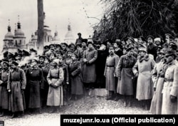 Урочистості з нагоди проголошення Української Народної Республіки на Софійській площі. Київ, 7(20) листопада 1917 року. Ліворуч: група військових. У центрі (зліва направо): генеральний секретар військових справ Симон Петлюра, голова Генерального секретаріату Володимир Винниченко, голова Центральної Ради Михайло Грушевський. Праворуч: військові та група військових аташе країн Антанти