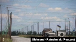 На фото видно згорілий транспортний засіб і сітки проти дронів, встановлені над дорогою поблизу прифронтового міста Добропілля, на тлі російського наступу на Україну, Донеччина, 10 серпня 2025 року