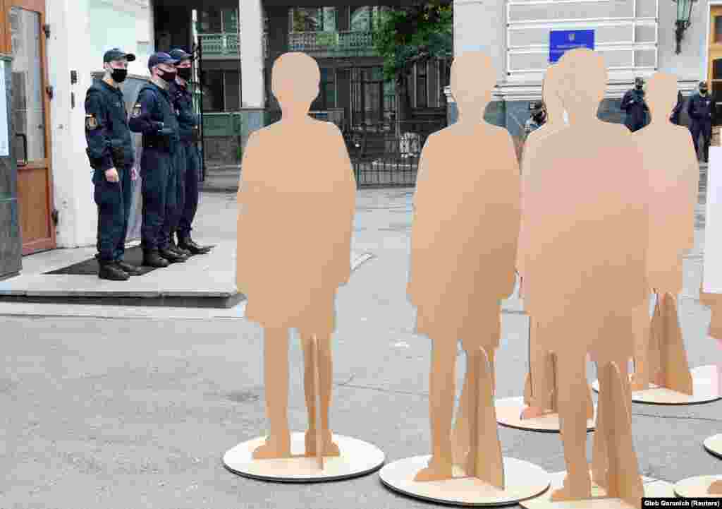 Поліцейські в масках на варті під час мітингу біля Міністерства охорони здоров’я в Києві. Мітингувальники дотримуються карантину. Людей здебільшого представляють манекени (REUTERS/Gleb Garanich)