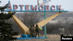 Українські вояки фотографуються біля таблички із вже неіснуючою назвою міста, 3 березня 2015 року