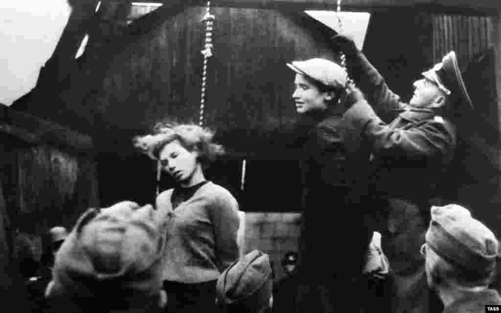 Німецькі офіцери і солдати готуються стратити Марію Брускіну і Володимира Щербацевича, учасників антинацистського опору, в Мінську в жовтні 1941 року. Незабаром після арешту Брускіної дівчина-підліток написала своїй матері: «Клянусь тобі, що через мене в тебе більше не буде неприємностей. Якщо зможеш, передай мені мою сукню, зелену кофтинку і білі шкарпетки. Я хочу бути пристойно одягненою, коли піду звідси»