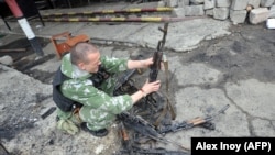 Проросійський бойовик оглядає пошкоджені автомати Калашнікова. Луганськ, 4 червня 2014 року