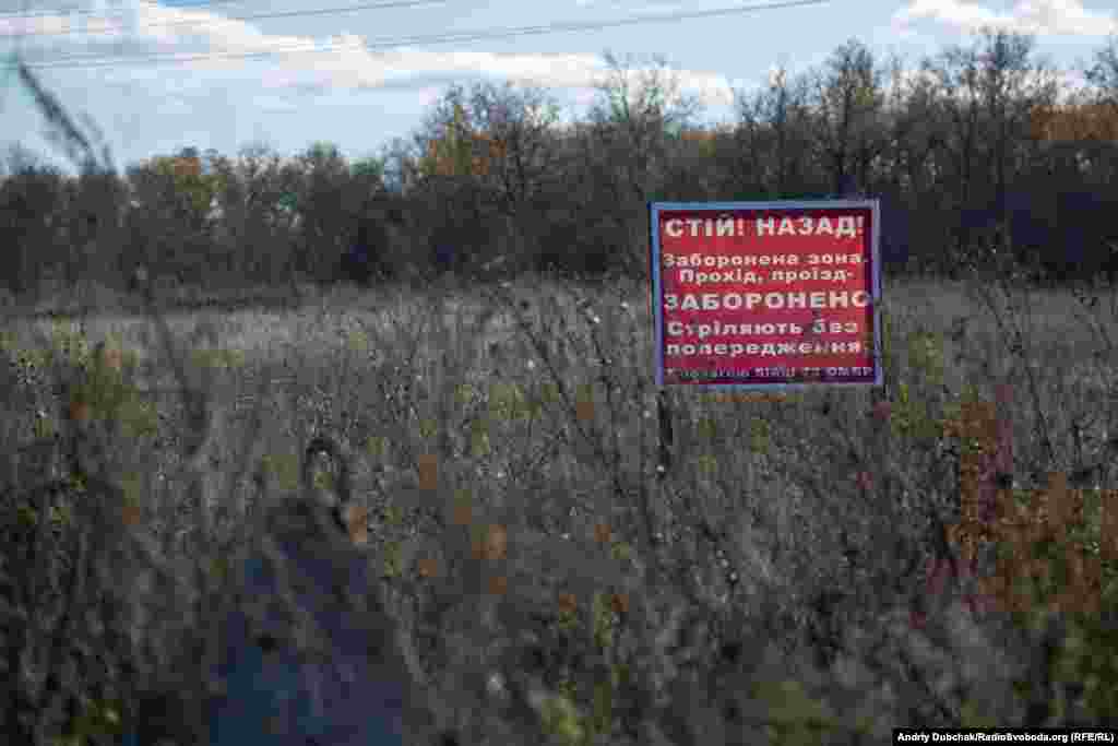 Йдемо пішки із Золотого-4 до Катеринівки, частина якої опинилася у «сірій зоні». Ліворуч від дороги чемні написи з застереженням, що стріляють без попередження. За посадкою раніше був «нуль», тепер військові відходять звідти