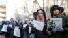 People hold posters with names of those killed in the Ukraine International Airlines flight PS752 during a commemoration ceremony in front of the Iranian Embassy in Kyiv in February 2020.