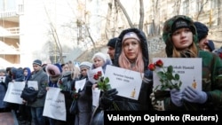People hold posters with names of those killed in the Ukraine International Airlines flight PS752 during a commemoration ceremony in front of the Iranian Embassy in Kyiv in February 2020.