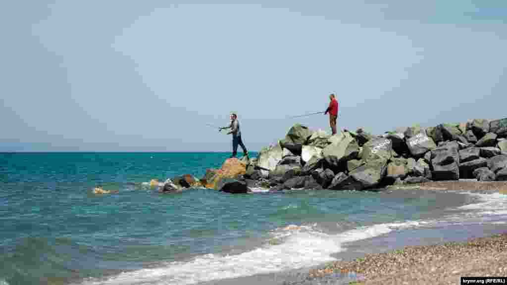 Двое мужчин рыбачат на «опасном» волнорезе из колотой скальной породы