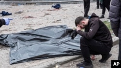 Чоловік плаче біля тіл загиблих після російського ракетного удару по Сумах, Україна, 13 квітня 2025 року