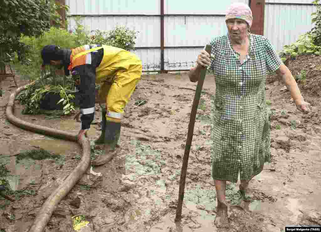 Сотрудник «Крым-Спас» и женщина во дворе затопленного дома