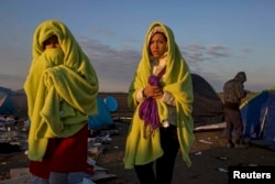 Migrants wrap themselves in blankets to warm up as the sun rises at a collection point in the village of Roszke, Hungary, on September 9.