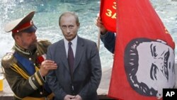 Чоловік в одязі, який робить його схожим на царя Миколу II (ліворуч), встановлює картонний виріз президента Росії Володимира Путіна, а інша особа з червоним прапором і зображенням Йосипа Сталіним, коли вони чекають туристів біля Червоної площі в Москві, 13 липня 2012 року