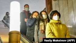 Люди у захисних масках спускаються на ескалаторі в метро (ілюстративне фото)