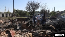 Місцеві жителі стоять на місці будівлі, зруйнованої російськими військовими у селі Ямпіль, Сумська область, Україна, 6 вересня 2024 року