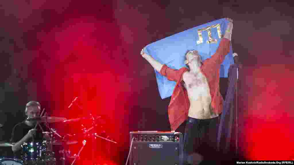 Святослав Вакарчук з прапором кримсько татарського народу під час концерту «Океану Ельзи» у Києві, 26 травня 2019 року