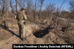 Український військовий оглядає вирву від 122-мм снаряду артилерії російських гібридних сил у селищі Болотяне, Луганська область, 23 листопада 2021 року