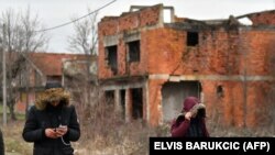 Manja skupina migranata prolazi pored napuštene zgrade u blizini blokiranog graničnog prijelaza na bosansko-hrvatskoj granici, u selu Bosanska Bojna u BiH, 30. siječnja 2021.