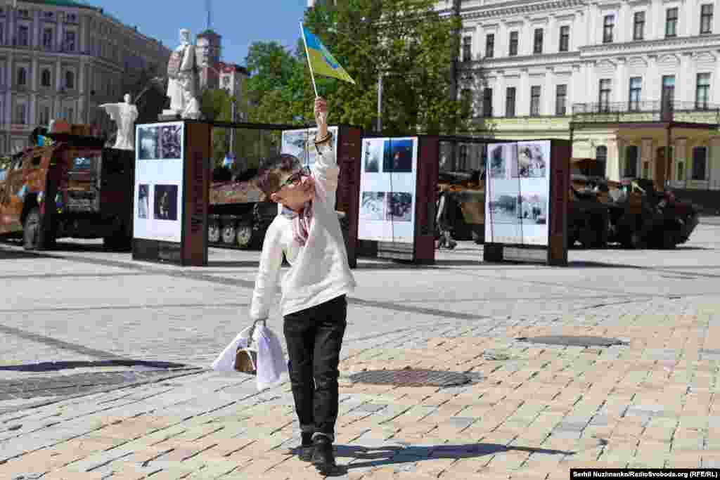 Хлопчик у вишиванці із прапором України та кошиком іде повз виставку
