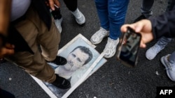 Демонстрант стоїть на фотографії президента Башара Асада під час протесту біля сирійського консульства в Стамбулі, 8 грудня 2024 року