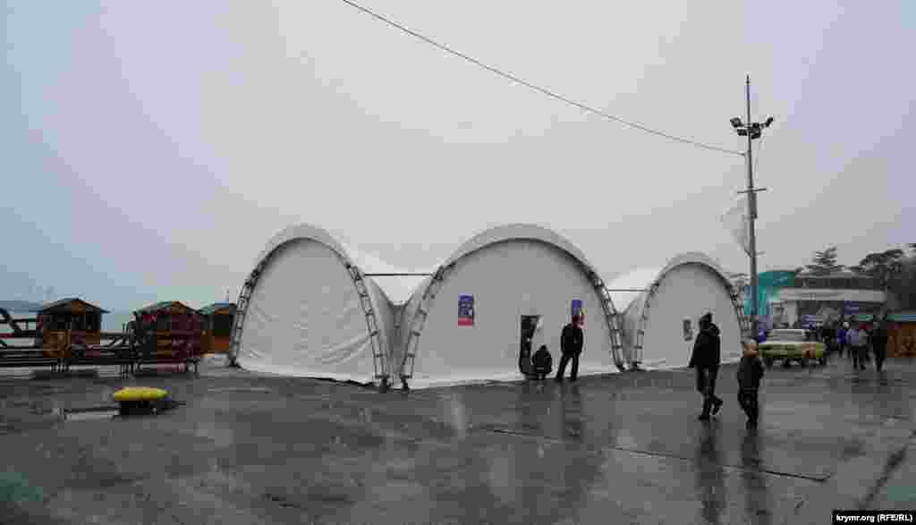 Сами приготовления к Рождеству в Ялте были заметны только близ  центральной набережной, где традиционно и проходят все торжества. Несмотря на обильный мокрый снегопад при температуре +3, рабочие возле главной новогодней собирали деревянные павильоны для аттракционов и деревянные домики