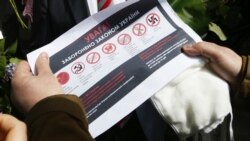 Правоохоронець тримає листівку зі списком комуністичної та нацистської символіки, забороненої в Україні. Київ, 9 травня 2020 року