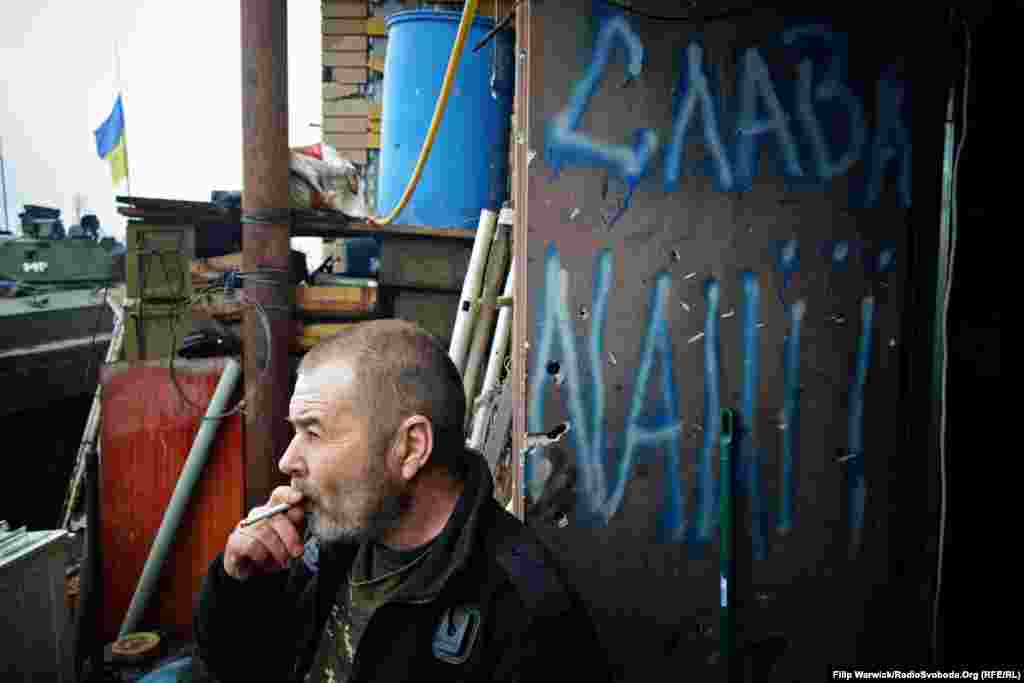 Военный 93-й бригады вышел на перекур у граффити «Слава нации!». Некоторые военные уверены, что Запад потерял интерес к конфликту на востоке Украины