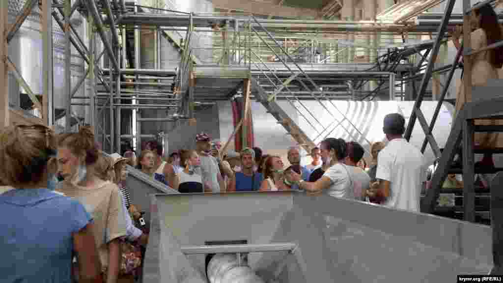 Экскурсионная группа на заводе. Экскурсовод рассказывает, как получают ферментированное (красное и розовое) вино. Экскурсия для взрослого обойдется в 400 рублей (150 грн), для ребенка – в 200 рублей (75 грн). Для посещения закрытых цехов обязательны маски