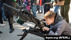 Ребенок со станковым гранатометом АГС 17 "Пламя" в руках на выставке сирийского оружия.