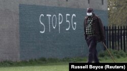 Чоловік у масці на обличчі під час спалаху коронавірусної хвороби (COVID-19) проходить повз графіті з написом «STOP 5G» в Лондоні, Великобританія, 8 квітня 2020 року.