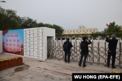Jurnaliștii străini fotografiază o locație din Xinjiang care încă din 2020 a fost identificată ca fiind un ccentru de reeducare. Guvernul dde la Beijing spune că este un centru pentru veterani care găzduieșet și alte birouri guvernamentale.