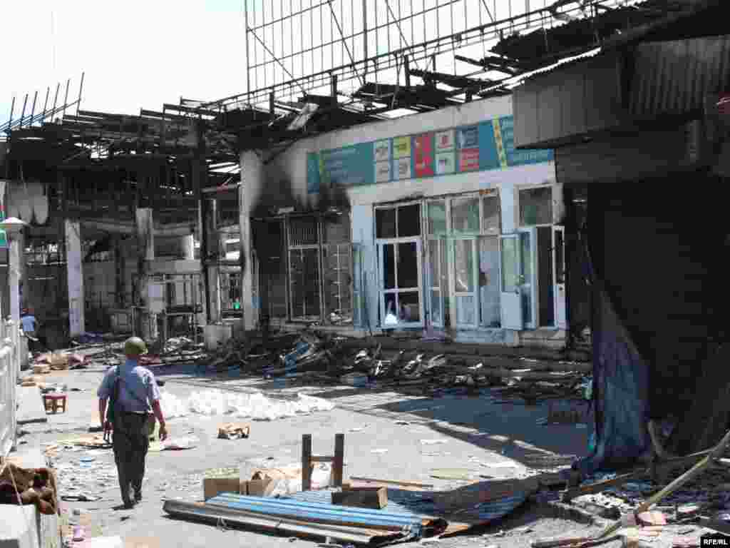 A policeman walks past burned buildings in Osh.