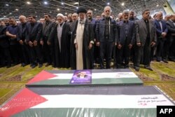 Верховный лидер Ирана Али Хаменеи руководит поминальной молитвой вместе с президентом Ирана Масудом Пезешкианом (в центре) над гробами убитого лидера ХАМАС Исмаила Хании и его телохранителя перед их похоронами в Катаре. Тегеран, 1 августа 2024 года