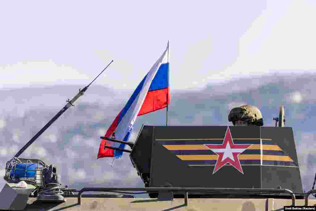 Російський стрілець на башті бронемашини на під'їзді до авіабази Хмеймім.  «Спілкуватися із російськими солдатами неможливо», – розповідає фотограф Бектас.  «Вони не відповідають на запитання і не підпускають до себе близько. Вони мають напружений вигляд, але не злий, вони не застосовують жодного насильства або чогось подібного», – додає він. – «Вони зберігають холоднокровність»  