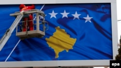 A worker fixes the national flag of Kosovo to a billboard ahead of Kosovo's fifth anniversary of its independence in Pristina in February 2013.