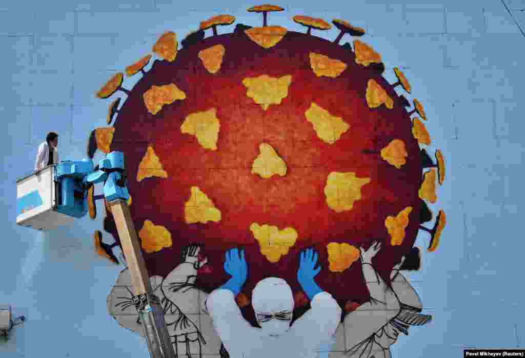 Художник працює над великим муралом в Алмати (Казахстан), який присвячений усім, хто перебуває на передовій у боротьбі країни проти COVID-19 (Reuters/Pavel Mikheyev)