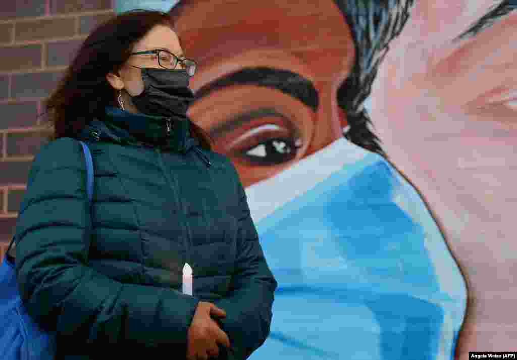 Жінка тримає свічку в ознаменування Всесвітнього дня боротьби зі СНІДом і смертей від COVID-19 в Нью-Йоркському центрі здоров’я, 1 грудня 2020 року