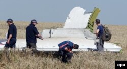 Australian and Dutch investigators examine a piece of debris from MH17 near the village of Hrabove, 100 kilometers from Donetsk, on August 1, 2014.