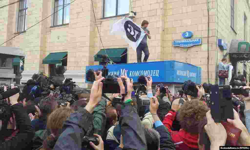 Участник акции залез на газетный киоск и развернул знамя с надписью "31". Позже его снял оттуда полицейский